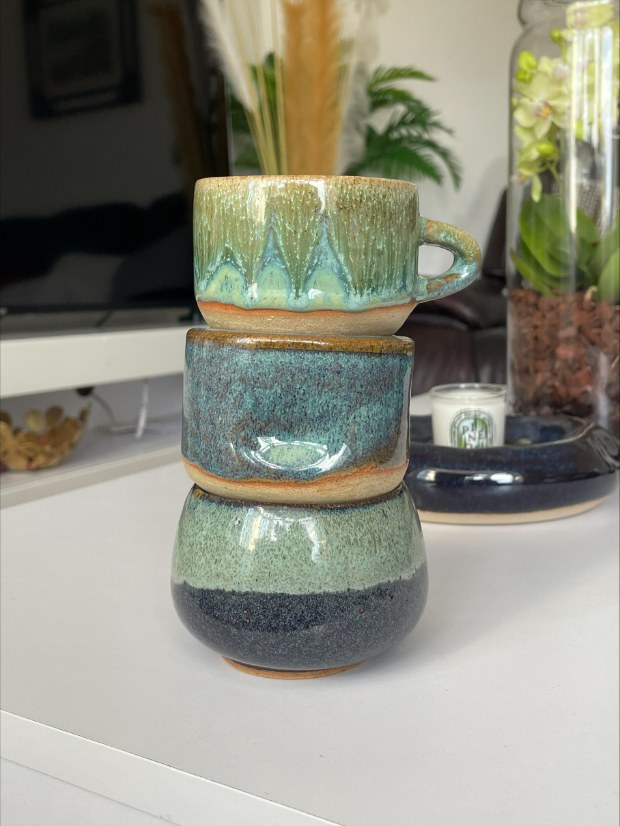Three stacked hand-thrown cups, glazed green and blue